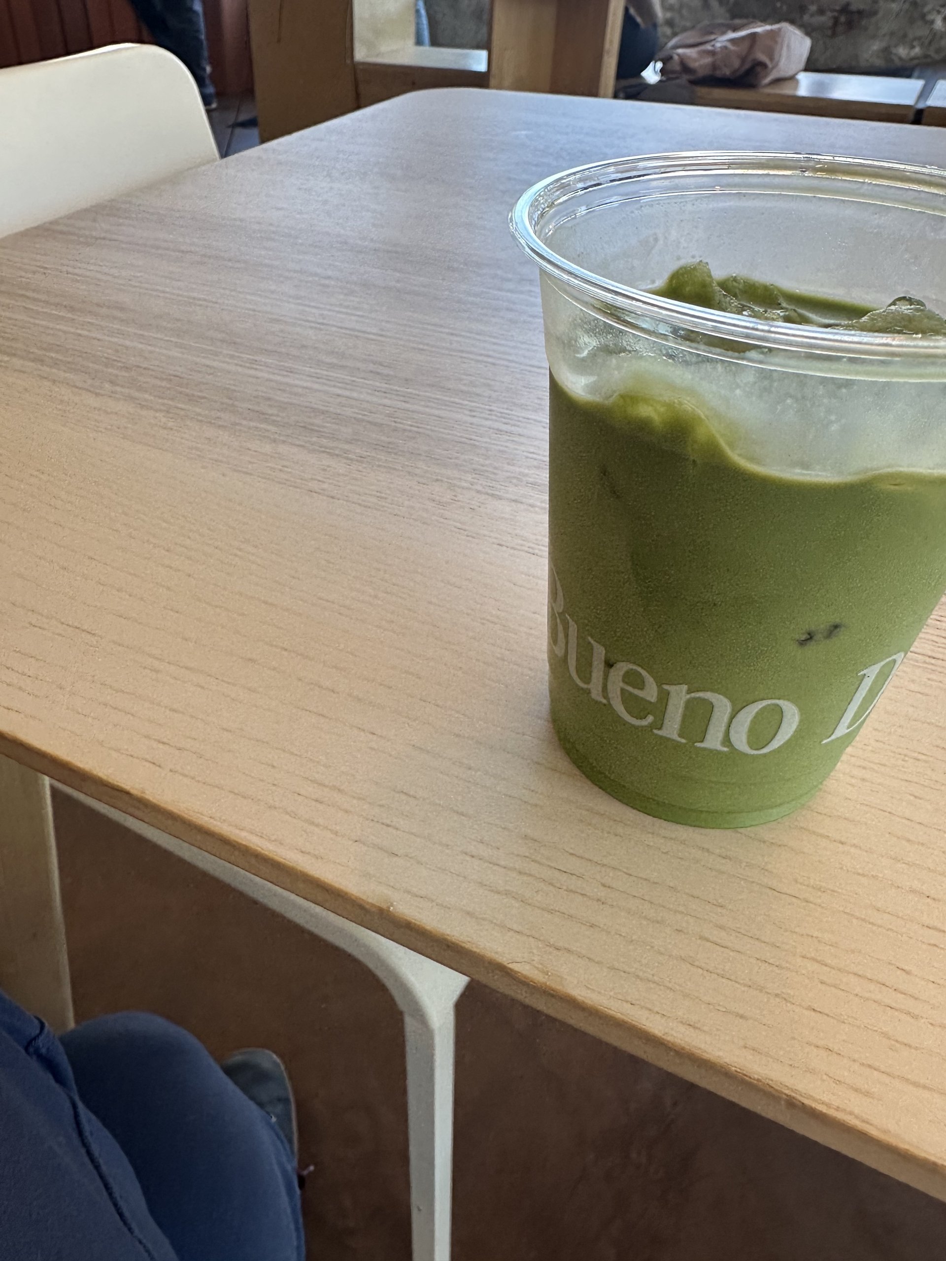 Iced masa matcha in a BuenoDays-branded cup on a wooden table