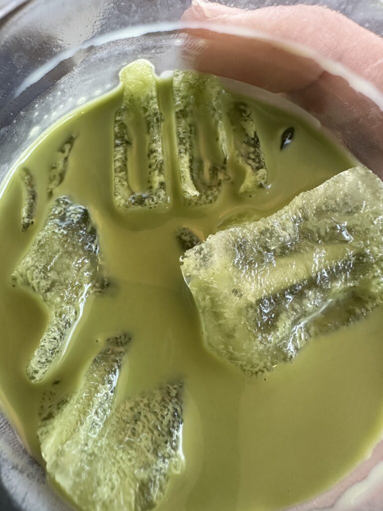 Top-down close-up of the masa matcha, pale yellow-green with matcha ice cubes
