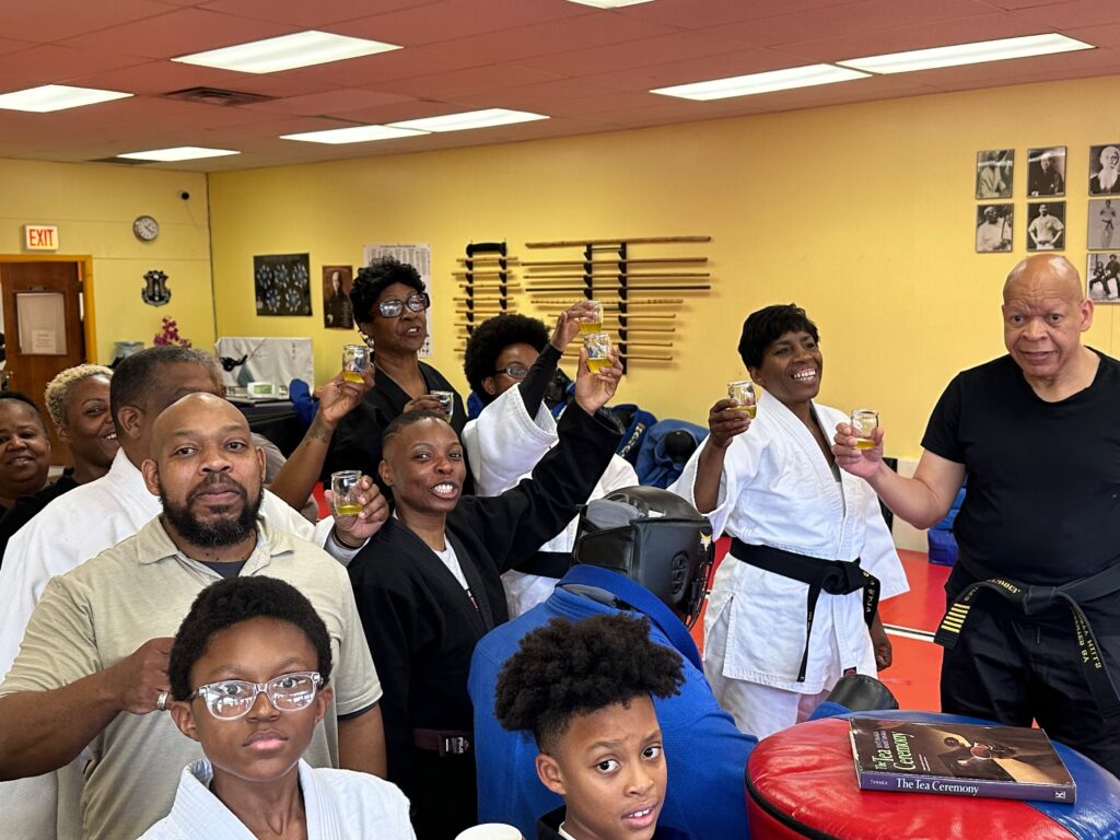 Chicago Matcha Club members and Beverly Pagoda martial arts students raising glasses of tea together in the dojo