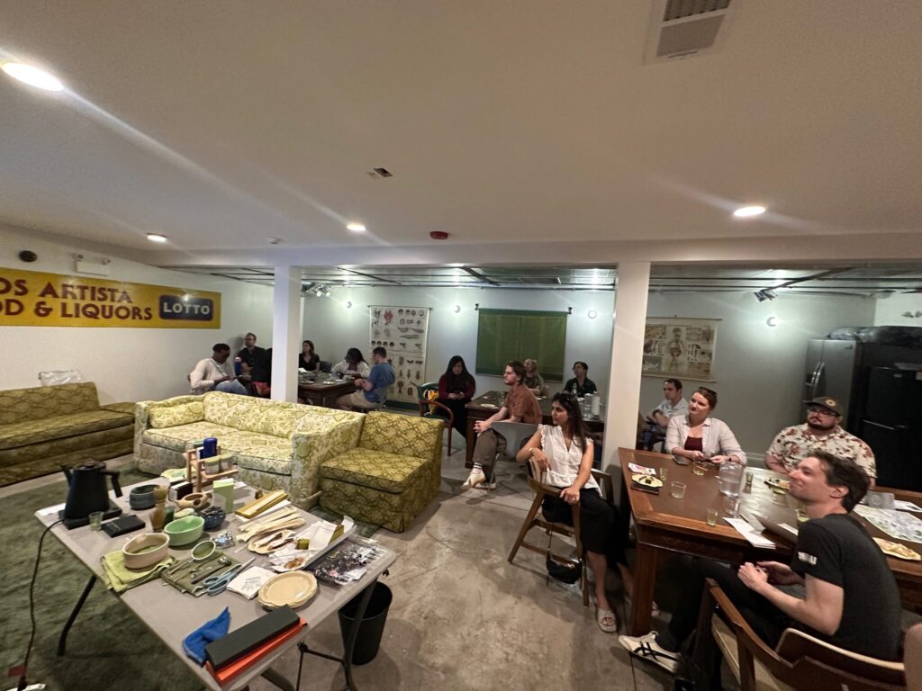 A full room of Chicago Matcha Club members on sofas and chairs at the Logan Inn, facing the hosts and a table of tea tools